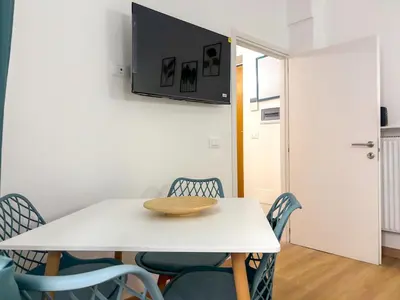 a white table with chairs and a television on a wall at Modern apartment with Private Balcony Near Colosseum in Rome