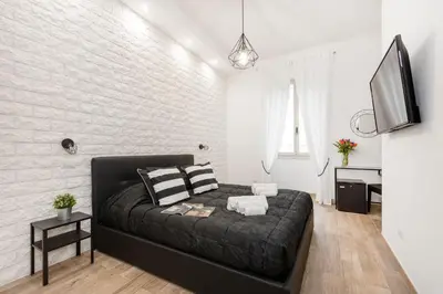 a bedroom with a black bed and a white brick wall at Black Rooms Colosseo in Rome