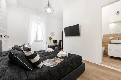 a bedroom with a bed with a television and a bathroom at Black Rooms Colosseo in Rome