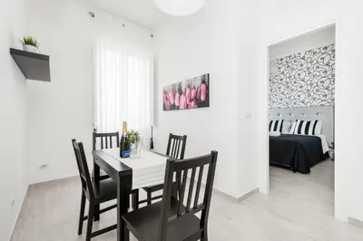 a white dining room with a table and chairs at Black Rooms Colosseo in Rome
