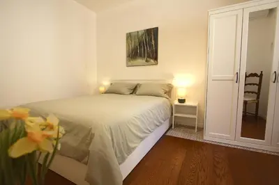 a white bedroom with a bed and a chair at Serpenti Holiday House in Rome