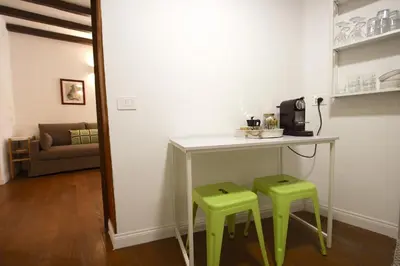 a kitchen with a table and two green stools at Serpenti Holiday House in Rome