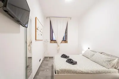 a white living room with a couch and a flat screen tv at Sallustiano - Porta Pia - Rooms in Rome