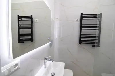 a white bathroom with a sink and a mirror at San Giovanni Suite Rome in Rome