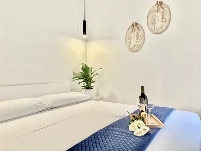 a white bedroom with a bed with a tray with wine bottles and glasses at San Giovanni Lulus Home in Rome