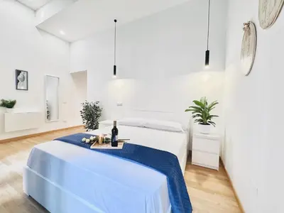 a white room with a bed with a blue blanket at San Giovanni Lulus Home in Rome
