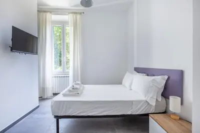 a bedroom with a bed with white sheets and a window at Ponte Milvio 3 Bedroom Apartment in Rome