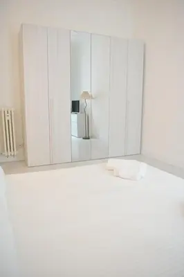 a white bedroom with a white bed and a mirror at Tasso 39 in Rome