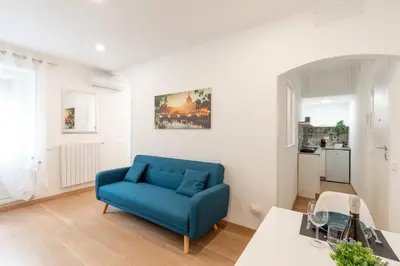 a living room with a blue couch and a kitchen at Ponte Milvio-Olympic Stadium Modern Apartment in Rome