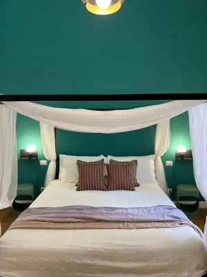 a blue bedroom with a white bed with two pillows at Eufonia Vatican Golden Suites in Rome