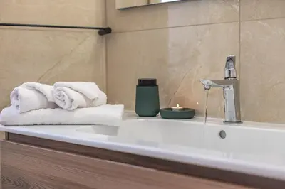 a bathroom with towels and a sink with a candle at Eufonia Vatican Golden Suites in Rome