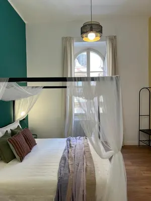 a bedroom with a bed with a canopy and a window at Eufonia Vatican Golden Suites in Rome