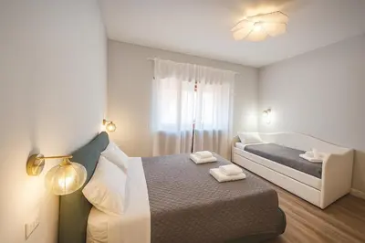 a white bedroom with a bed and a couch at Sole 34 Apartment in Rome