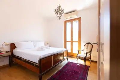 a bedroom with a bed and a chair and a window at Casa Arezzo - silenzioso trilocale con terrazzino privato - Cale 06 in Rome