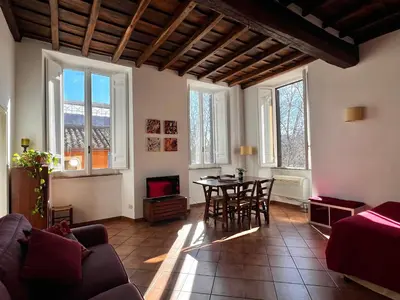 a living room with a table and chairs and windows at Finestre sul Tevere in Rome