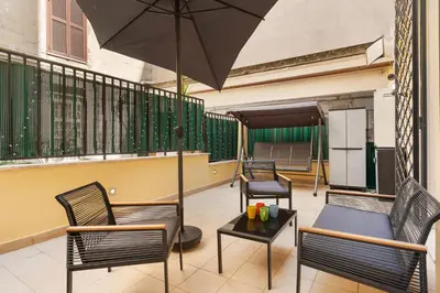 a patio with chairs and an umbrella on a balcony at Quintino Terrace Apartment near Termini Station in Rome