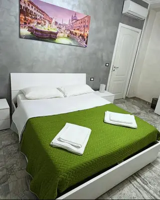 a bedroom with a bed with green sheets and towels at Cataldo Suites Roma in Rome