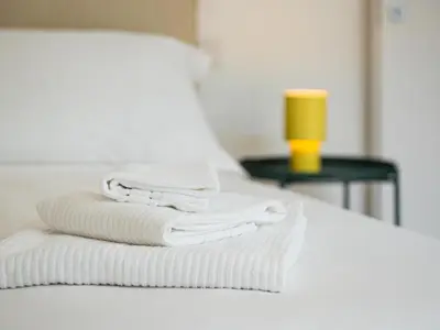 a stack of towels on a bed with a yellow cup at Pop House Labicana in Rome
