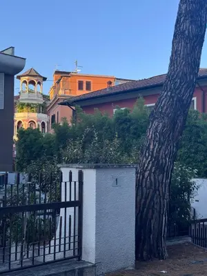 a fence next to a building with a clock tower at La Casetta Monteverde in Rome