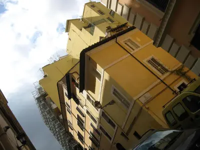 a tall yellow building with windows on the side of it at Musa Apartments in Rome