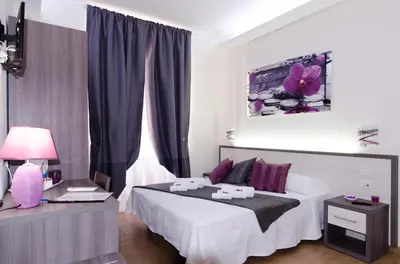 a bedroom with a white bed with purple pillows at Gemme Di Roma Accomodation in Rome