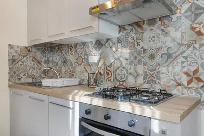 a kitchen with a stove and a tile wall at Conca D'Oro Guest House - Anna in Rome