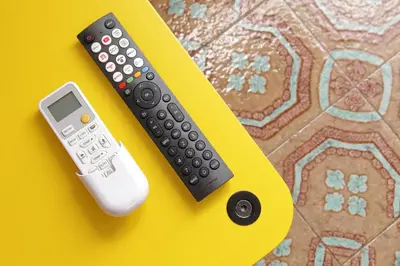 two remote controls sitting on a yellow table at Trastevere 70 in Rome