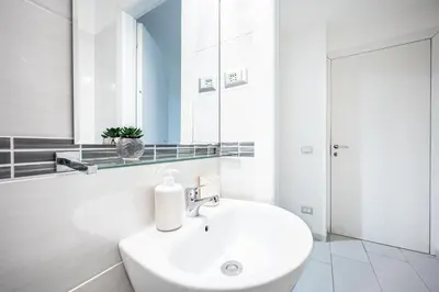 a white bathroom with a sink and a mirror at Domus Lodi Urban Stay I Affittacamere in Rome