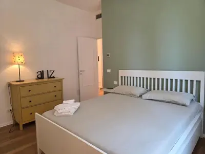 a bedroom with a white bed and a dresser with a lamp at Maison Viola in Rome
