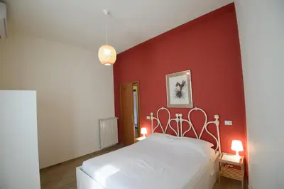 a bedroom with a white bed in a red wall at Appartamento Iris in Rome
