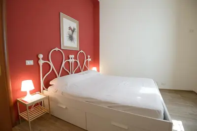 a bedroom with a white bed with a red wall at Appartamento Iris in Rome