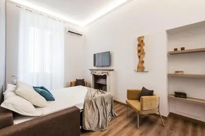 a living room with a bed and a chair at The Best Rent - Three-Room Apartment with View of the Portico d'Ottavia in Rome