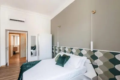 a bedroom with a white bed with green pillows at The Best Rent - Three-Room Apartment with View of the Portico d'Ottavia in Rome