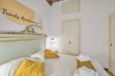 a bedroom with a bed with white sheets and yellow pillows at Trinity Apartment in Rome