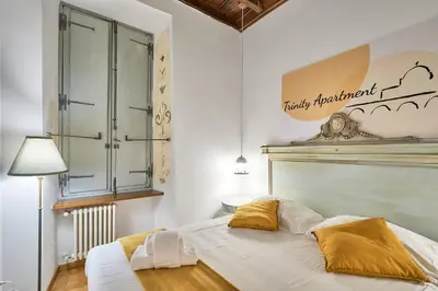 a bedroom with a large bed with white sheets and yellow pillows at Trinity Apartment in Rome