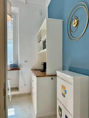 a kitchen with white cabinets and a blue wall at Vacanze Romane Suite 7 Languages in Rome