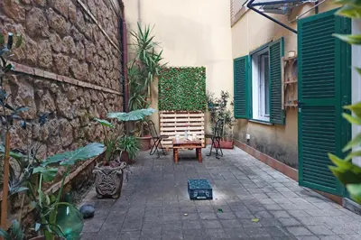 a courtyard with a bench and a wall with green shutters at Charming Nest Steps from the Vatican in Rome