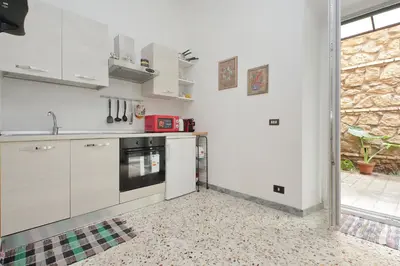 a kitchen with white cabinets and a tile floor at Charming Nest Steps from the Vatican in Rome