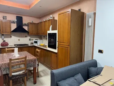 a kitchen with wooden cabinets and a table with a couch at A Casa di Mary in Rome