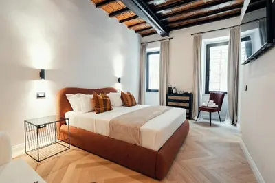a bedroom with a bed and a desk and windows at The Rubens Spagna in Rome