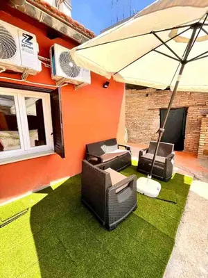 a patio with an umbrella and chairs on grass at Pigneto Holiday Home in Rome