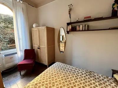 a bedroom with a bed and a mirror and a chair at 7550rome P&J's cozy Trastevere Apartment in Rome