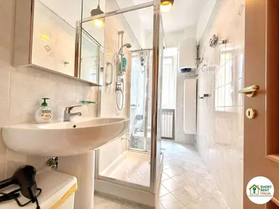 a white bathroom with a sink and a shower at San Giovanni - Minerva House in Rome