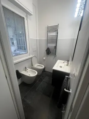 a white bathroom with a toilet and a sink at Mina's House in Rome