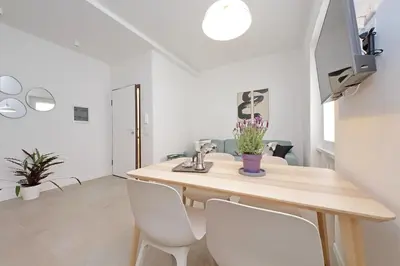 a dining room with a wooden table and white chairs at Brand New Modern Apt 2 Stops to Colosseum in Rome