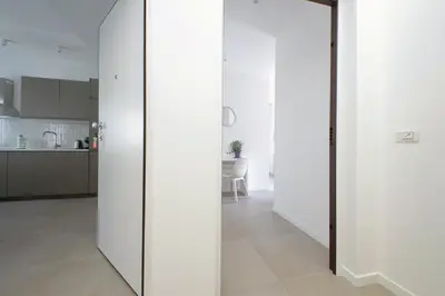 a hallway with white walls and a white kitchen at Brand New Modern Apt 2 Stops to Colosseum in Rome