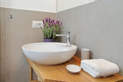 a bathroom with a white sink on a wooden counter at Brand New Modern Apt 2 Stops to Colosseum in Rome