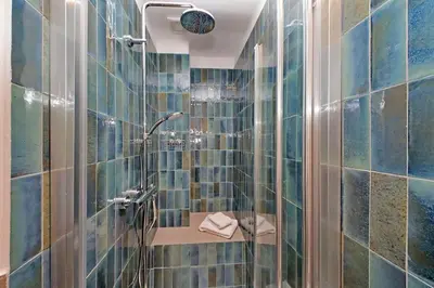 a bathroom with a shower with blue tiles at Brand New Modern Apt 2 Stops to Colosseum in Rome