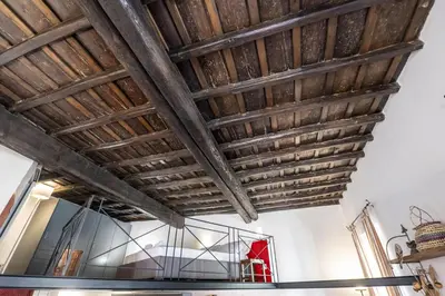a room with a wooden ceiling and a glass table at The Scarlet Loft in Trastevere in Rome