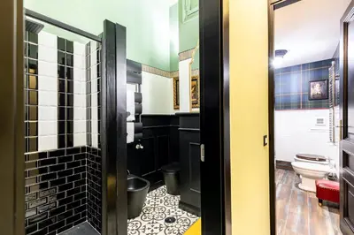 a bathroom with black and white tiled walls and a toilet at Rome As You Feel - Maison Torre Argentina - Arenula 41 in Rome